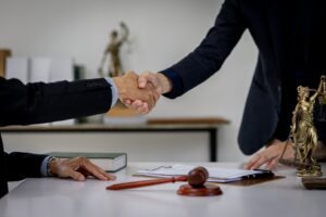 A lawyer shaking hands with a client who is wondering if they should get a lawyer for a minor car accident.